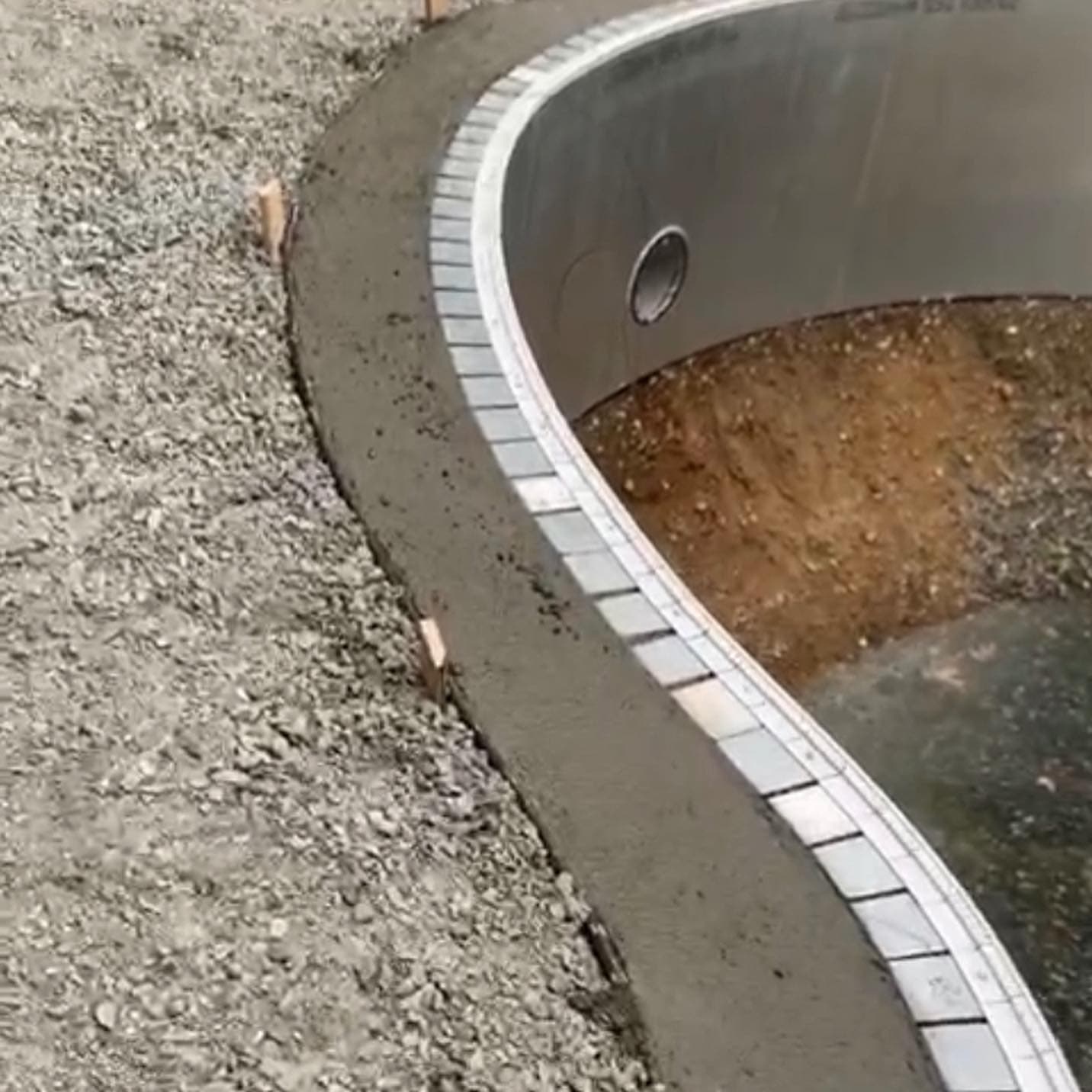 Bullnose paver coping being set along a pool edge