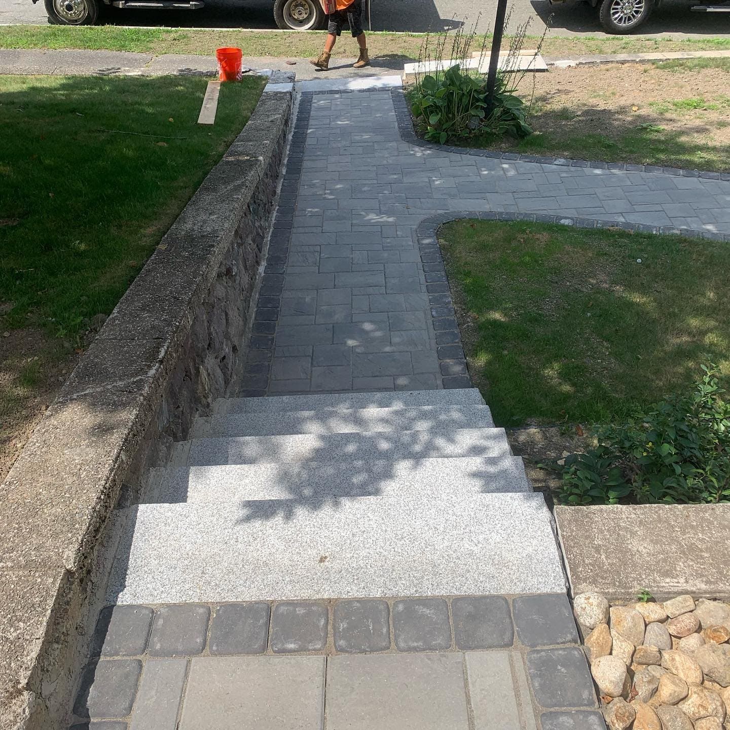 Granite steps leading down to a paver walkway beside a stone wall
